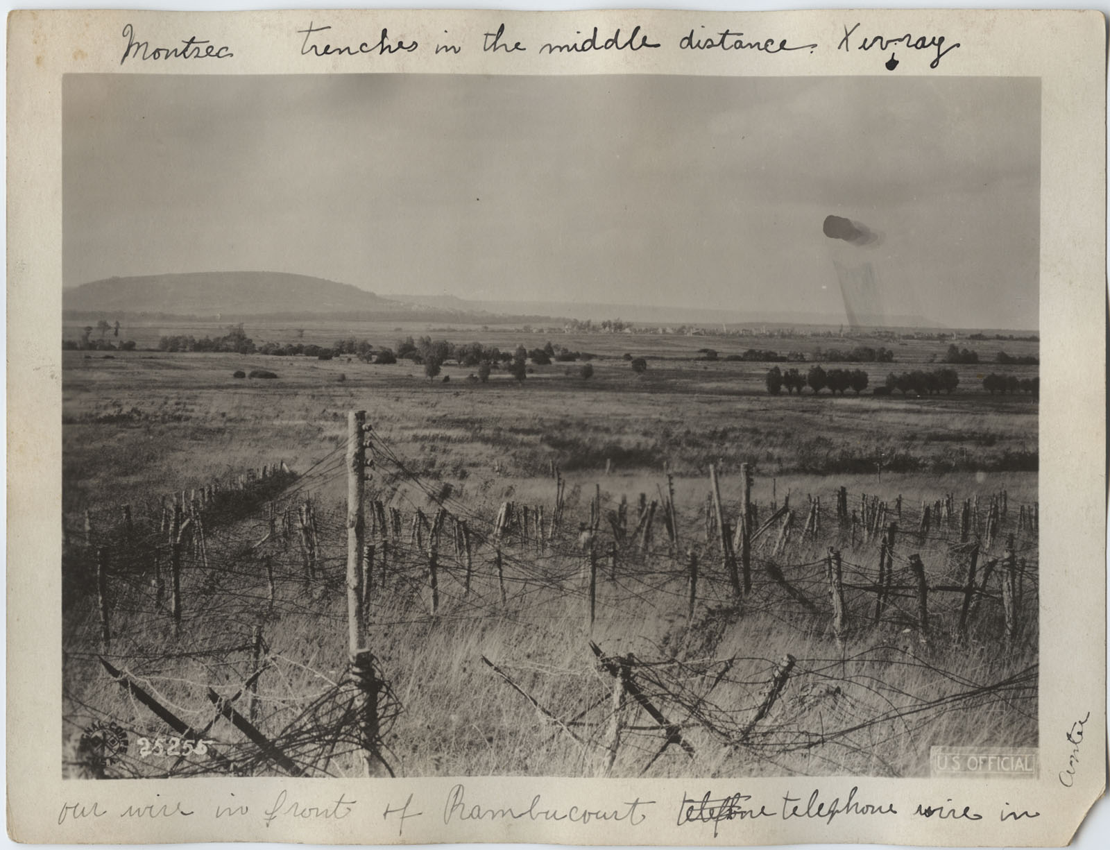 Black and white photograph of a field covered in barbed wire, with a hill rising in the distance.