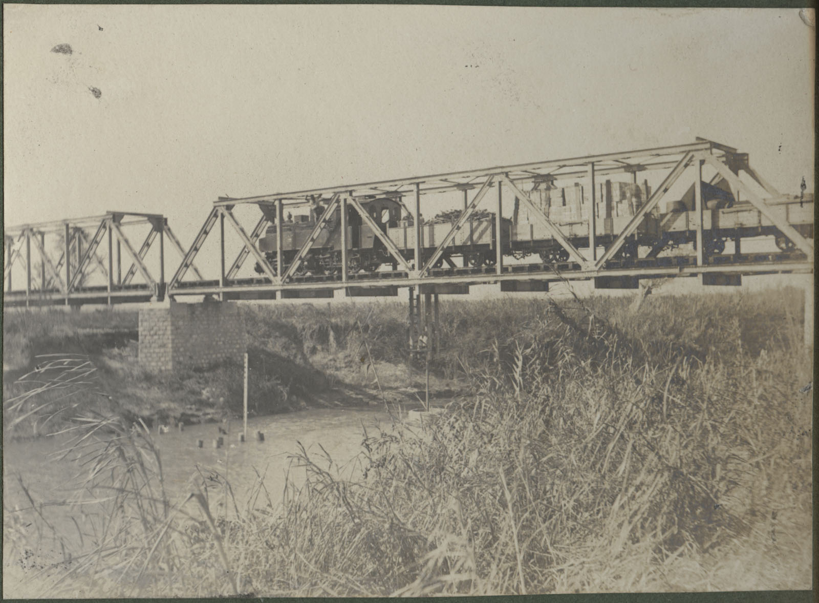 Black and white photograph of a train going over a bridge over a river