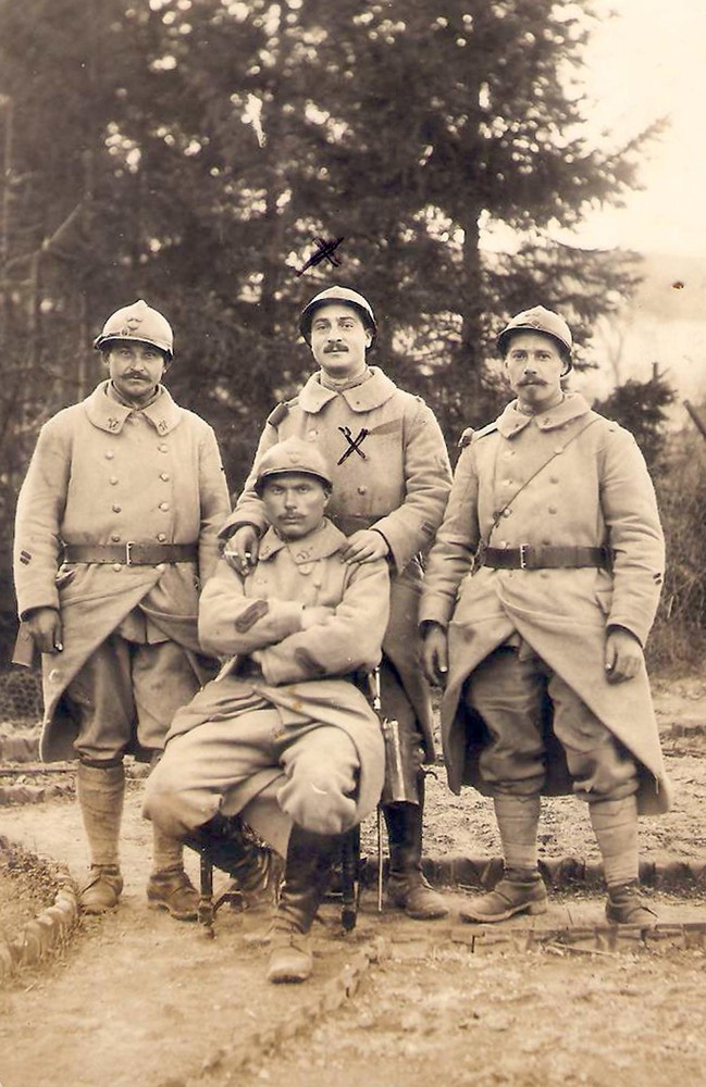 Sepia portrait photo of a group of four WWI soldiers standing or sitting in a forest clearing.