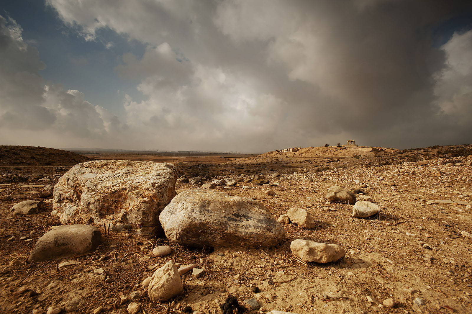 Modern photograph of a sandy, rock-strewn landscape. 
